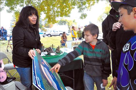 Gerald Meyers and Roper Wayman listen to Eleanor Vizcarra explain what a proposed innovative playground will look like in Ronan.