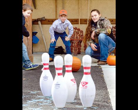 Levi Conover, 7, watches to see if the pumpkin goes in the right direction to knock over his pins. 