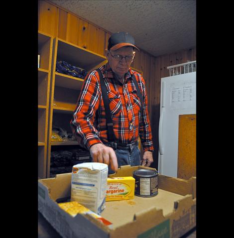 Volunteer Bob Burrell fills a box with supplies from the Ronan Bread Basket.