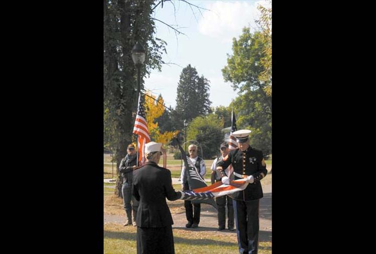 Sgt. Sharon Brannan and Sgt. Chuck Lewis of the Marines fold the American flag while three Freedom Riders watch from behind.