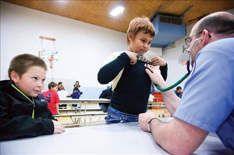 John Dressen, an R.N. from St. Luke Health Center, listens to a students heart.