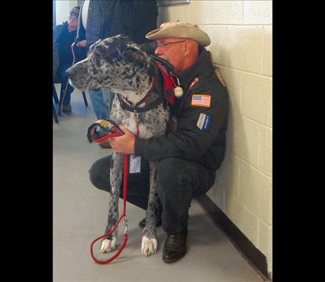 Bill Austin, Quilt of Valor recipient, receives a hug from a little girl and a snuggle from his Great  Dane, J.