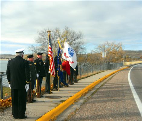 Members of the American Legion, Post 112 in Polson stand at attention along the Armed Forces Memorial Bridge in Polson at 11 a.m. on Nov. 11.