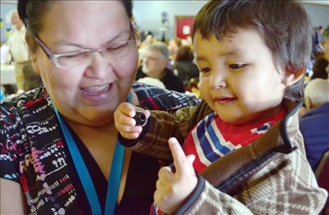 Cameron Michel, 2, tries to stick an olive on his finger while in the arms of Lucinda Michel.
