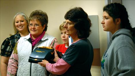 K-Ann Delong, left, Shelley Croft, Chubby Chicks basketball, Ethan McCauley, coach, and Mikayla Croft, cheerleader, look on as Millie Nesladek, Linderman Elementary School nurse, holds the automated external defibrillator the Chubby Chicks donated to the district.