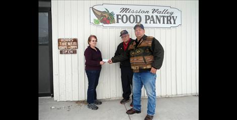Homer Courville, adjutant of the American Legion James R.W. McCarthy Post 106, center, and Legionnaire Vic Stevens present a check in the amount of $577 to the Mission Valley Food Pantry in St. Ignatius.
