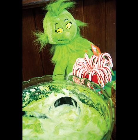 The Grinch guards a bowl of green punch.