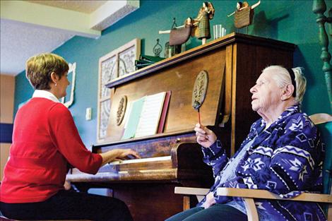 Kathleen Sweeney plays piano as Alice Estes plays the jingle bell.
