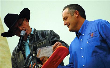 Montana Livestock Auction co-owner Blake Nuffer, left, confers with Western Montana Stockgrowers Association President Kurt McPherson about an auction item.