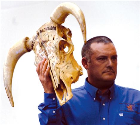 Western Montana Stockgrowers Association President Kurt McPherson holds up a decorated cow skull as ranchers bid on it.