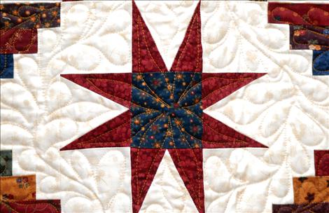A star surrounded by feather quilting sits in the center of a quilt in the All in Stitches Quilt Walk.