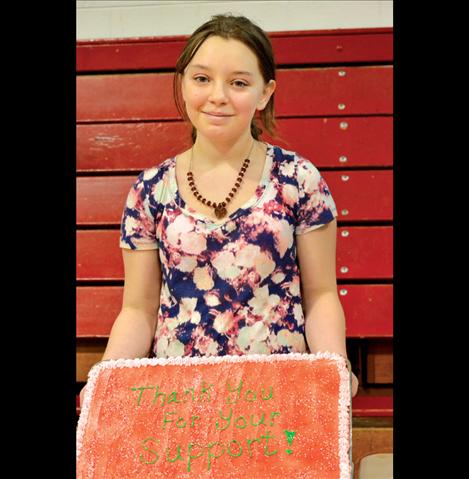 Keisha Dillard, 12, holds up a cake before it was sliced during the fundraiser for her family, who lost everything when their home burned to the ground in December.