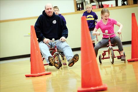 Polson High School math teacher James McKee participates in a tricycle race.