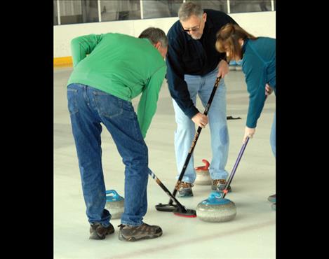  Curlers Gayle Seimers, left, Allen Bone and Wendy Scheffler sweep to keep the stone sliding. 
