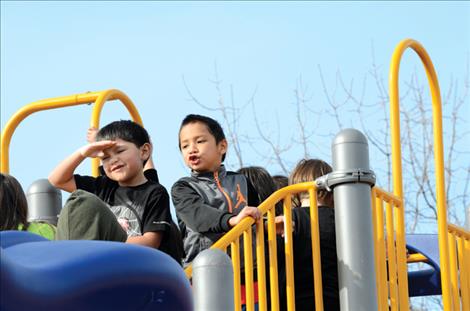 Children grin from ear to ear while playing on new equipment in St. Ignatius.