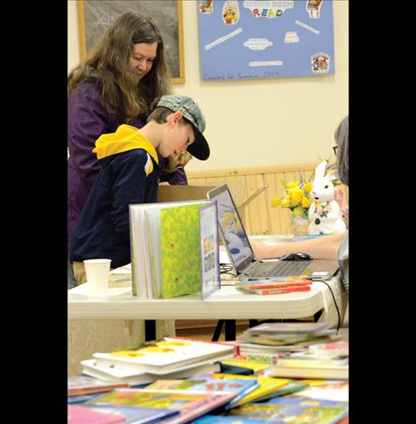 August Starratt, 10, of Arlee signed his name after donating books to help volunteers keep track of donations.