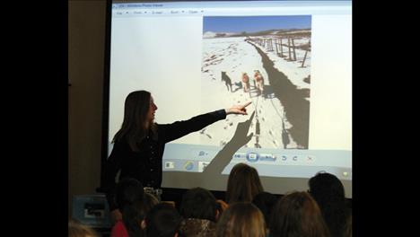 Charmayne Morrison points to a video of her dogs running in the snow this winter as she explains the sport to Polson Middle School kids.