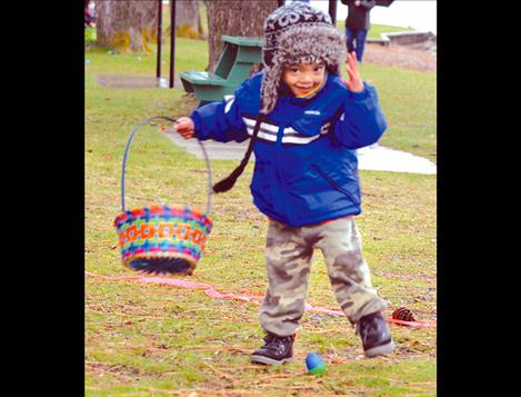 Ceasar Johnson, 2, stays warm in an oversized hat while hunting for eggs in Polson’s Boettcher Park.