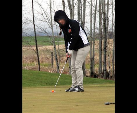 Bundled up to fight the chilly spring weather freshman Brooklyn Olson putts on the soggy green. Olson placed first at Ronan’s home tournament and then went on to place fourth in Plains on Saturday.