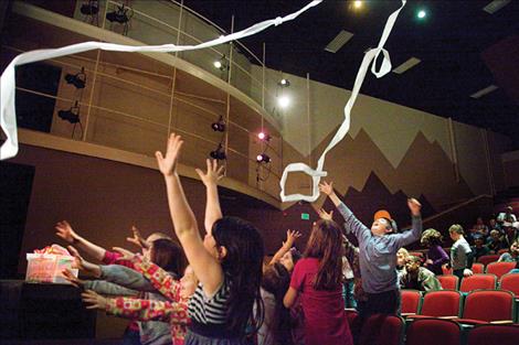 Children clamor for toliet paper thrust into the air during a physics demonstration. 