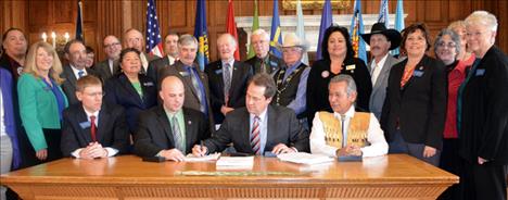Governor Steve Bullock signs legislation ratifying the Confederated Salish and Kootenai Water Compact as members of the state legislature and tribal government look on. 