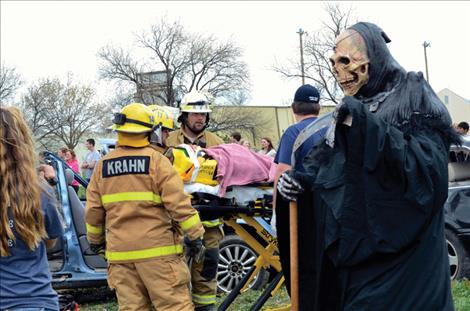 A grim reaper mills among emergency workers at a mock accident scene. 