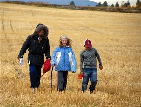 Students Grace Hobbs and Elijah Taylor walk through a field with Jennifer Hobbs.
