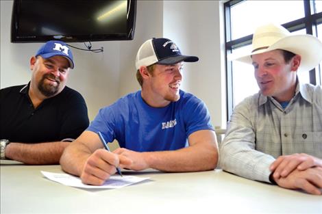 Mission High School senior Will Powell signs a letter of intent Thursday, joining the Montana State University rodeo team on a four-year scholarship. Seated with Powell are, left, Matt Young, Mission High School shop teacher and Tech Club advisor; and Beau Clark, right, Bobcat rodeo assistant coach.