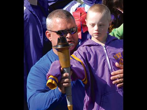 Polson Police Chief Wade Nash carries the Special Olympics torch with athlete Kyler Gage. 