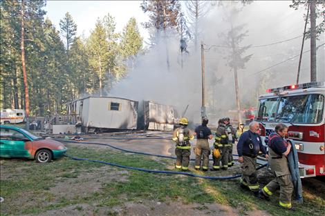 onan and Finley Point firefighters run hoses to two smoldering trailers. 
