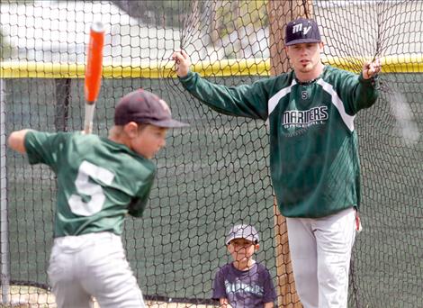 Left: Mission Valley Mariners slugger Izyke Gillingham coaches a young camper in the batting cages during the 2015 Mariners baseball camp and coaches clinic Saturday morning at O’Malley Park in Polson.  