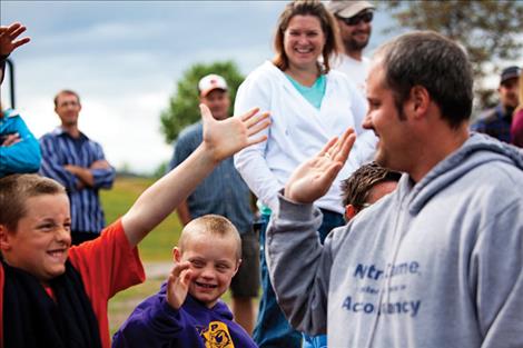 Ryan Gage, left, high fives his sons after he threw a good rock.