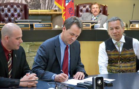 Senator Chas Vincent, Governor Steve Bullock, Tribal Chairman Vernon Finley and Representative Dan Salomon, not pictured, gather around a table in the Council Chambers Thursday as Bullock ceremoniously signs the passage of the water  compact.