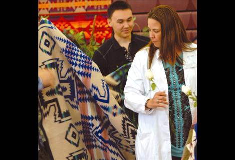 A nursing graduate accepts a traditional Pendleton blanket during the blanketing and pinning ceremony.