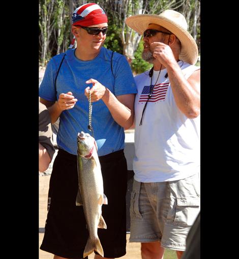 Brad Brown shows off his lake trout as he talks to boat captain Tony Anderson. 