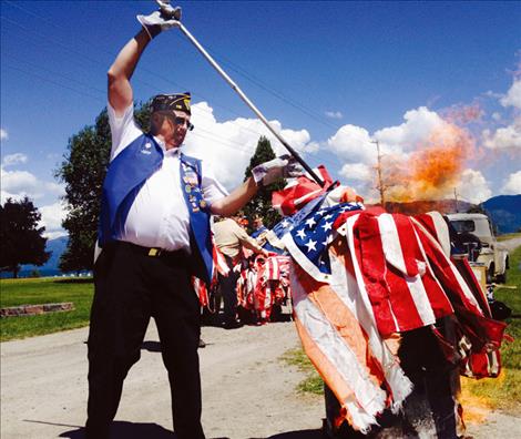 On Flag Day, Jeff Nelson, District Treasurer with the American Legion Hardwick Post 112, retires worn stars and stripes at Lakeview Cemetery in Polson.
