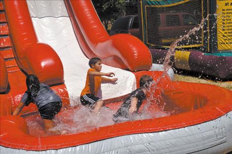 Kids cool off via water slide in triple-digit temperatures.