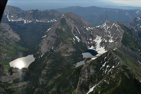 Sean Fragua looks down at the rugged tops of the Mission Mountains that rut like a dragon’s spiny backbone into the sky during a tour with Blue Goose Aviation