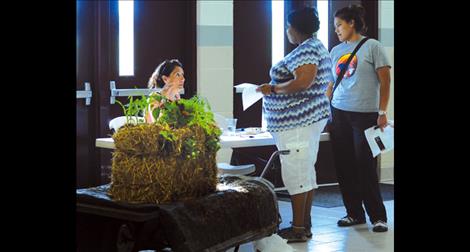 Berl Tiskus/Valley Journal A volunteer at the Communities at Play family fun night talks with parents about planting a straw bale garden.