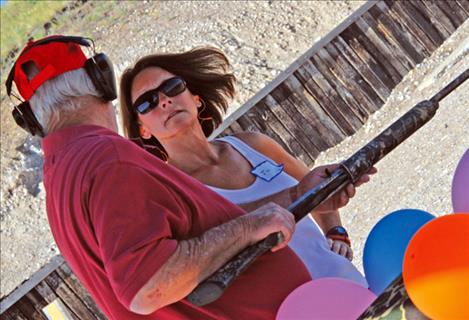 Jil Roberts talks with the gun’s owner as she steps up to the line to shoot a shotgun.