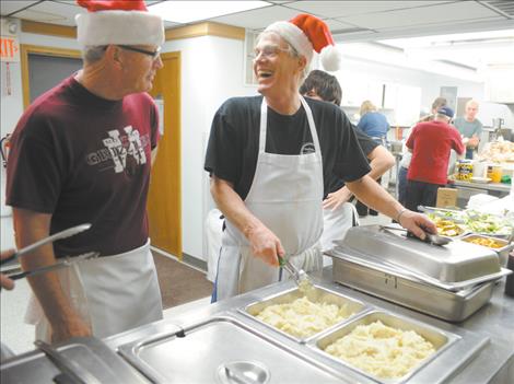 Burt Cannon, center, demonstrates how to scoop mashed potatoes on the serving line for the Christmas dinner at the Ronan Community Center.