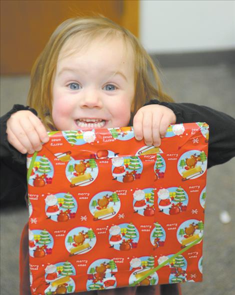 Kila Cannon excitedly displays a gift Santa gave her during a community Christmas dinner held Dec. 25 at the Ronan Community Center.