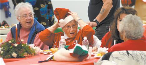 Jim Blow/Valley Journal Marie Cowen adjusts her festive cap before sitting down for her meal at the Traditional Christmas Day Dinner held at the Ronan Community Center on Christmas Day. Cowen had so much catching up to do with friends that her dinner began to get cold. "That's fine. Cold dinner doesn't bother me," the former cafe owner smiled. "I actually digest it better when it's cold."