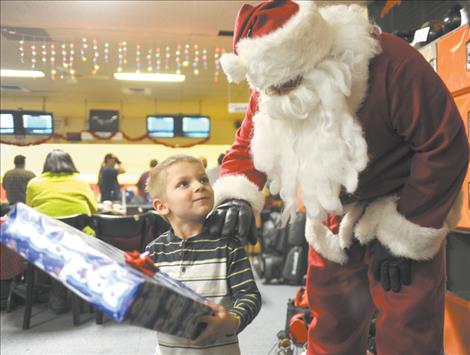 Charley Rathbun happily accepts a gift from Santa Claus, who visited him last Tuesday evening. Santa was escorted by the Ronan Fire Department aboard a fire engine. Each year, RFD firefighters donate to the Ronan Firemen's Christmas program to buy presents for local children.