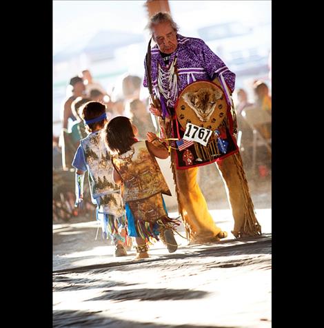 Elder Francis Stanger exits the dance floor as small dancers wave at him. 