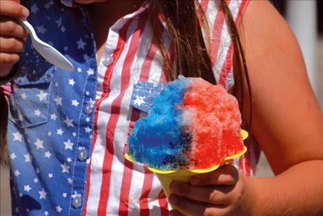 Shelly Torgenrud, age 2 of Ronan, plops down to remove her shoe, which has given her a blister. Above right, the Montecahto Club sold out of their famous cherry pies. Above right, Emma Kupper, 10, of Philadelphia, Pennsylvania, eats a red, white and blue shaved ice.