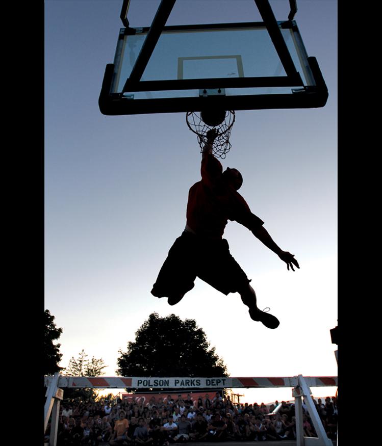 Matt Luedtke, a Ronan High School graduate, leaps over a barrier borrowed from the Polson Parks Department during the slam dunk contest at the Flathead Lake 3-on-3 basketball tournament in Polson. Luedtke’s moves impressed the crowd and the judges, but he just missed his final dunk attempt to fall short of the $1,000 prize.