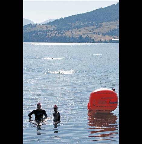 Swimmers take a breather at the finish line in Big Arm Sunday morning.