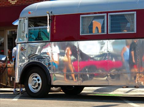 A shiny bus reflects images of visitors to last year’s car show