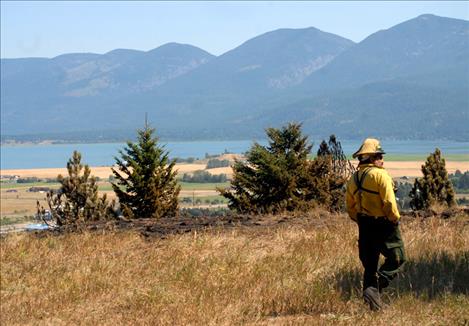 A firefighter with the Confederated Salish and Kootenai Division of Fire watches the burned area Tuesday morning.